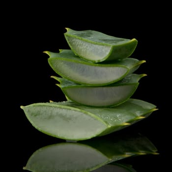 Sliced aloe leaf and water drops isolated on black background.