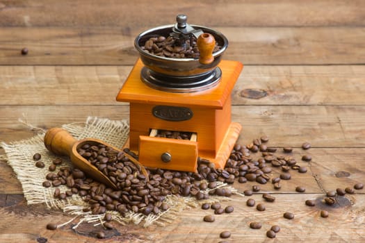 coffee grinder on wooden background with roasted coffee beans