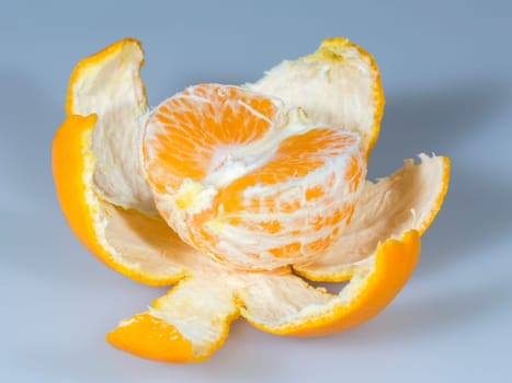 Half Clementine with Peal close up on grey background.