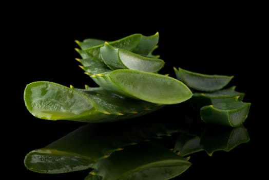 Sliced aloe leaf and water drops isolated on black background.