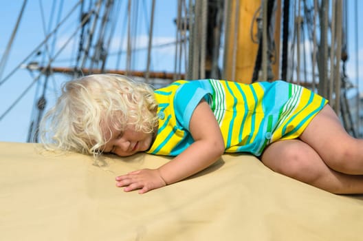 the little girl fell asleep on the deck of a sailboat