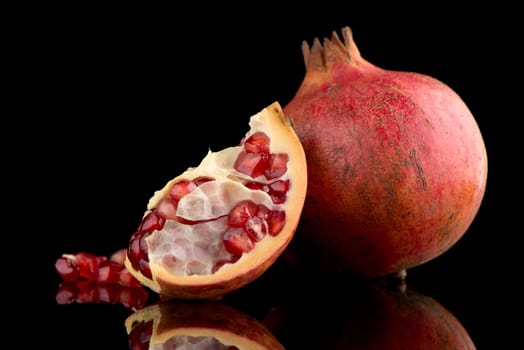 Ripe pomegranate fruit with leaves on black background