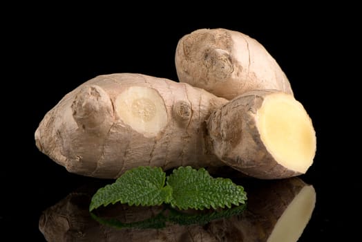 Ginger root on black reflective background.
