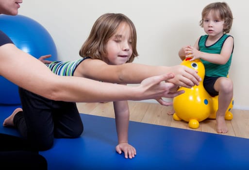 a female physiotherapist makes physiotherapy with young children