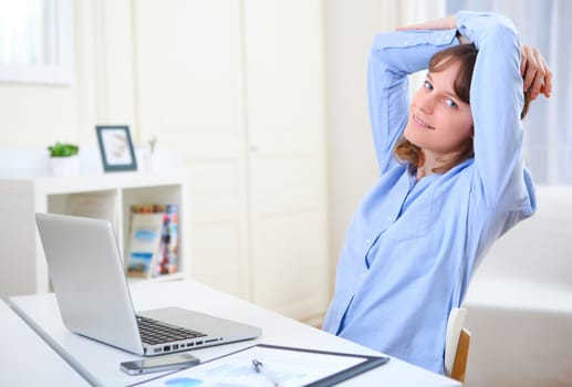 View of a young smiling business woman relaxing at work