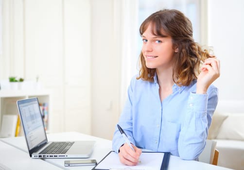 View of a young attractive business woman copying data on paper