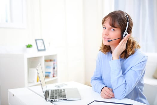 View of a young smiling business woman working at home