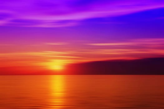 Burred sunset above the sea. Golden and red sea and purple sky.