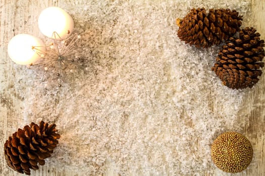 Wooden Christmas background with candle and pine cones..