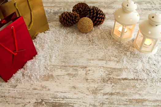 Wooden Christmas background with candles, pine cones, shopping bags and baubles..