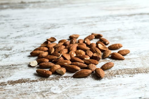 Many almonds over a wooden table, background.