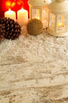 Wooden Christmas background with candles, pine cones, shopping bags and baubles..