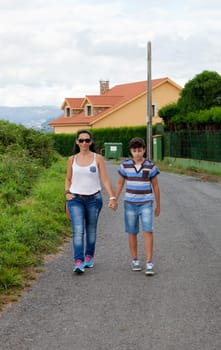 Woman with her son walking with a house background
