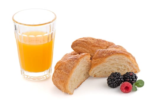 Glass of orange juice, fresh croissant , raspberries and blackberries on white background
