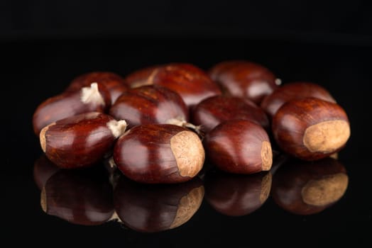 Closeup of chestnuts on a black reflective background.