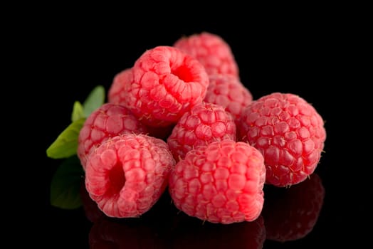 Raspberries with leaves isolated on black background background