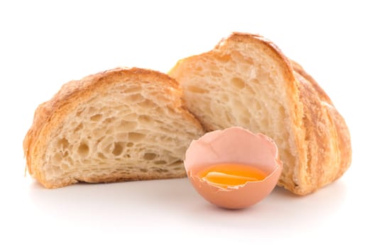 Fresh croissant and raw egg on white background