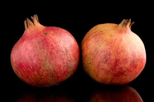 Ripe pomegranate fruit with leaves on black background