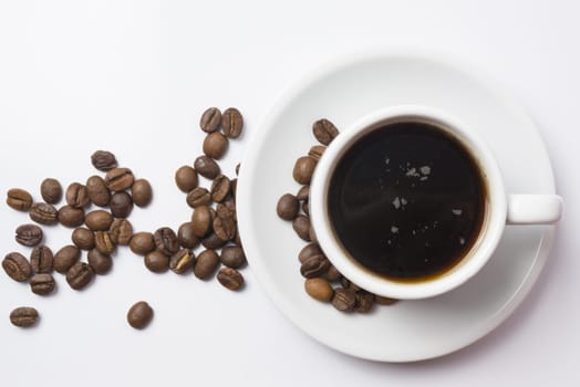 Top view, traditional cup of black coffee with beans over white background. Clipping path included, so you can easily copy and paste it on your own design.