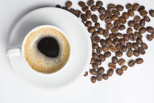 Classic cup of coffee with foam and scattered roasted beans, top view angle. Clipping path included, so you can easily copy and paste it on your own design.