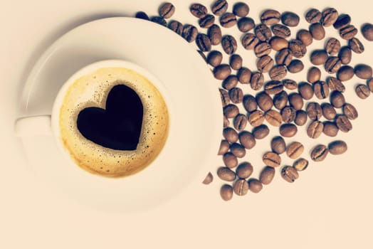 Vintage cup of coffee top view with beans and heart shape made on foam, love concept. Includes clipping path, so you can easily copy and paste it on your own design.