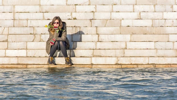 girl sitting at the river bank at the other side of the river