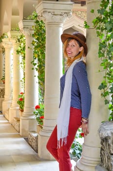 girl with a hat leaning against a pillar