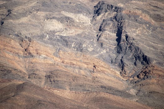 The close-up of a mountain with different rock layers and faults.