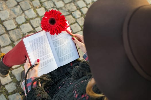 Romantic girl with a book and red gerbera flower
