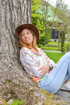 girl leaning against a tree in the park