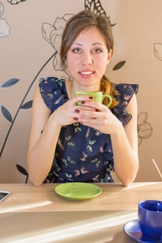 Smiling brunette drinking coffee at the kitchen table