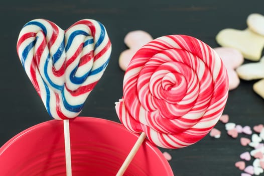 heart shaped lollipop and a round lollipop in a red vase