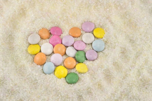 colorful bonbons arranged to make a heart in sugar