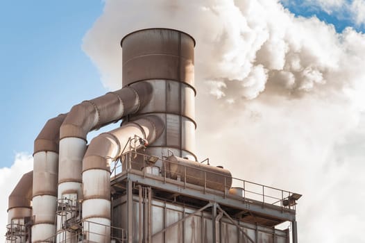 Old smokestack that emits white smoke.