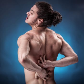 Young athlete who has a painful twinge on blue background