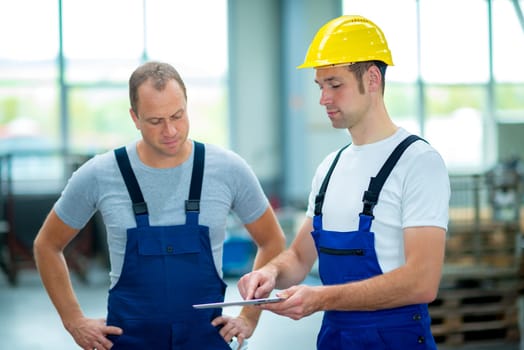 two young worker in factory using tablet pc