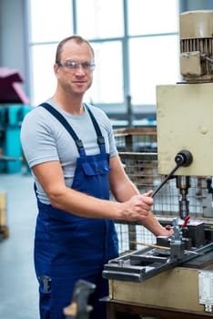 young worker in factory using drill machine