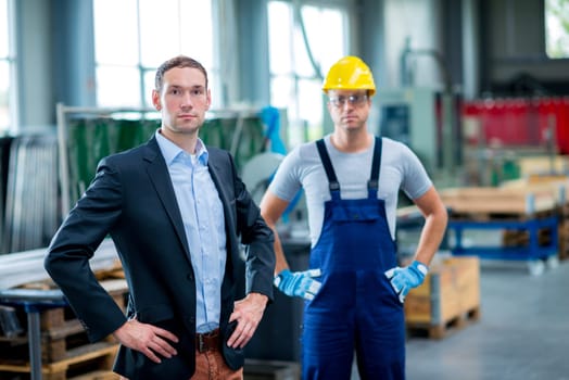 young boss with worke in the background in his factory