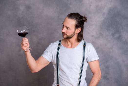 young man in front of gray background drinking red wine