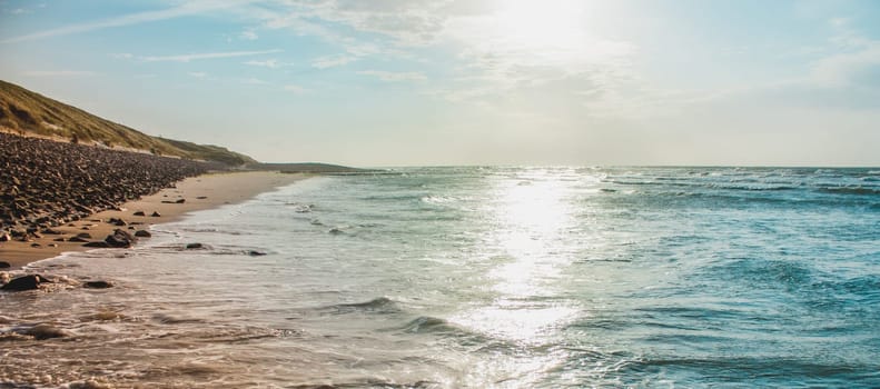 An endless sandy beach and a lonely surfer in the blue sea