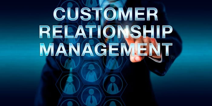Business manager is touching CUSTOMER RELATIONSHIP MANAGEMENT onscreen. Business concept and technology metaphor. Male and female customer icons embedded in hexagons do signify collected client data.