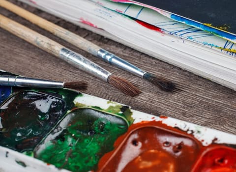 Paints and brushes on a wooden background closeup