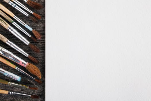 brushes for painting  and blank white paper sheet on vintage wooden  background