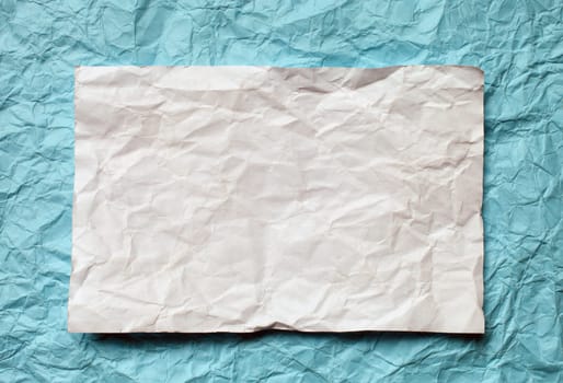 Crumpled  white paper card on cyan  background, place for tex