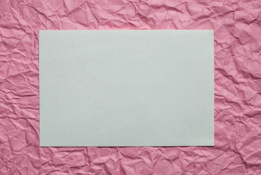 Crumpled  white paper card on pink background, place for tex