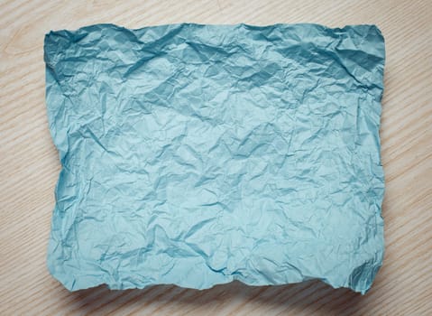 Crumpled  cyan paper card on beige background, place for tex