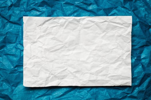 Crumpled  white paper card on blue background, place for tex
