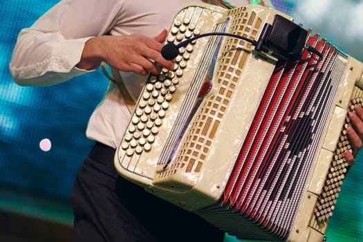 Closeup detail of hands playing a black accordion instrument