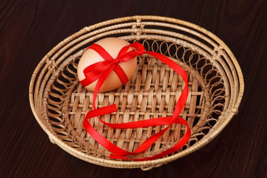 festive Easter egg in wooden bowl with red ribbon isolated