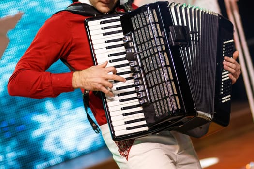 Closeup detail of hands playing a black accordion instrument